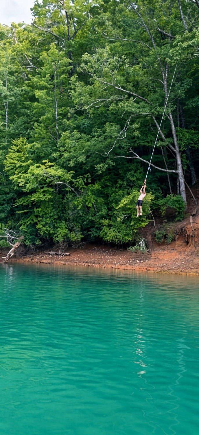 Guest swinging from a rope over turquoise Lake Blue Ridge water