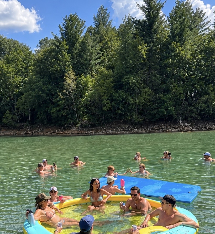 Guests relaxing in the water and on a float near the boat